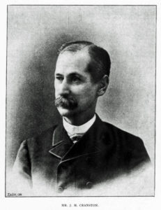A black and white photograph of J.H. Cranston. He is a white man, looking off screen. He has smooth, slicked down hair and a bushy mustache. 